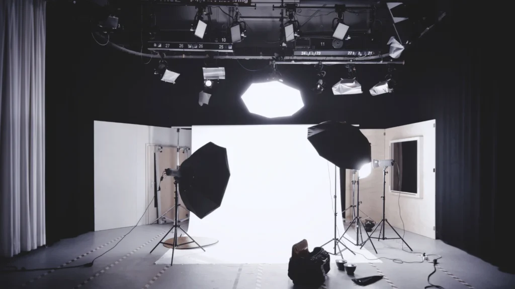 Full film studio lit with multiple octabox and overhead rig lighting fixtures against a white backdrop