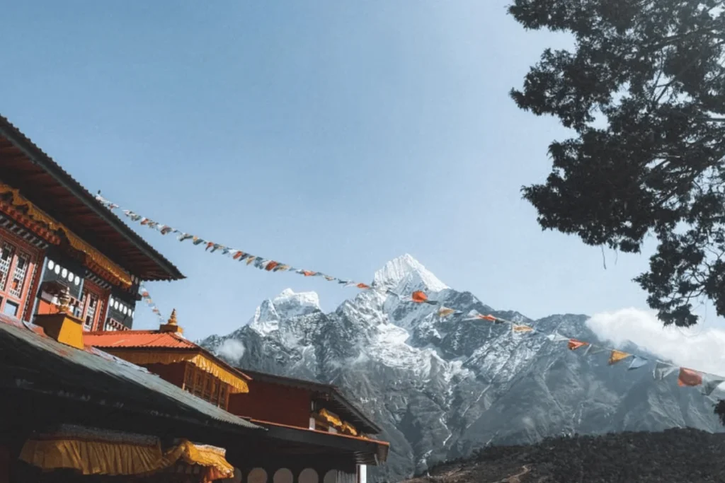 Colorful prayer flags stretching across a snow-capped Himalayan peak near a monastery in Nepal for photography adventure