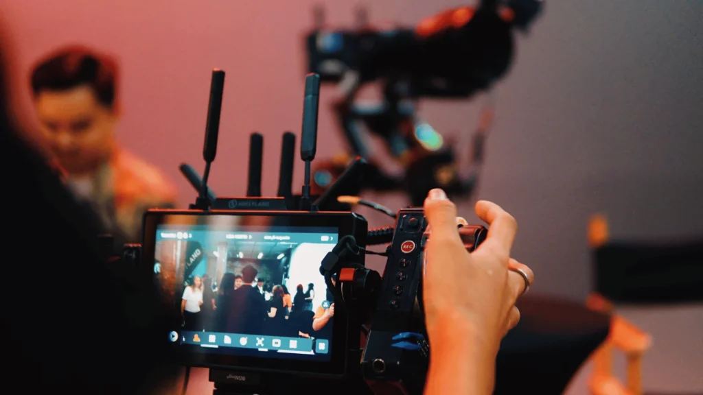 Wireless video monitor with Hollyland antennas mounted on a camera rig, showing a live feed of a film set